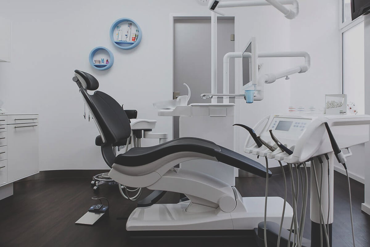 Modern dental clinic interior with advanced equipment, a black dental chair, and clean, bright decor.